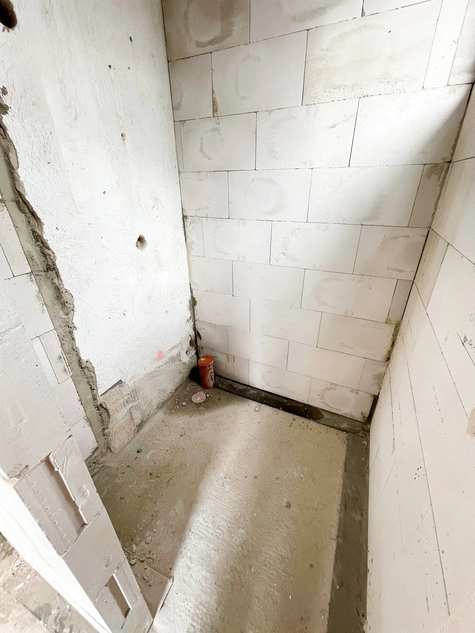 Kleiner Raum im Rohbau mit unverputztem Mauerwerk und Betonboden